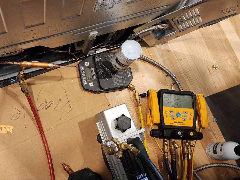 Refrigerant gauges, scale and vacuum pump connected to a refrigerator